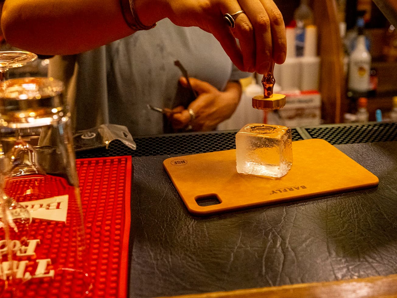 A branding stamp pressed into a hand-cut clear ice cube at the bar